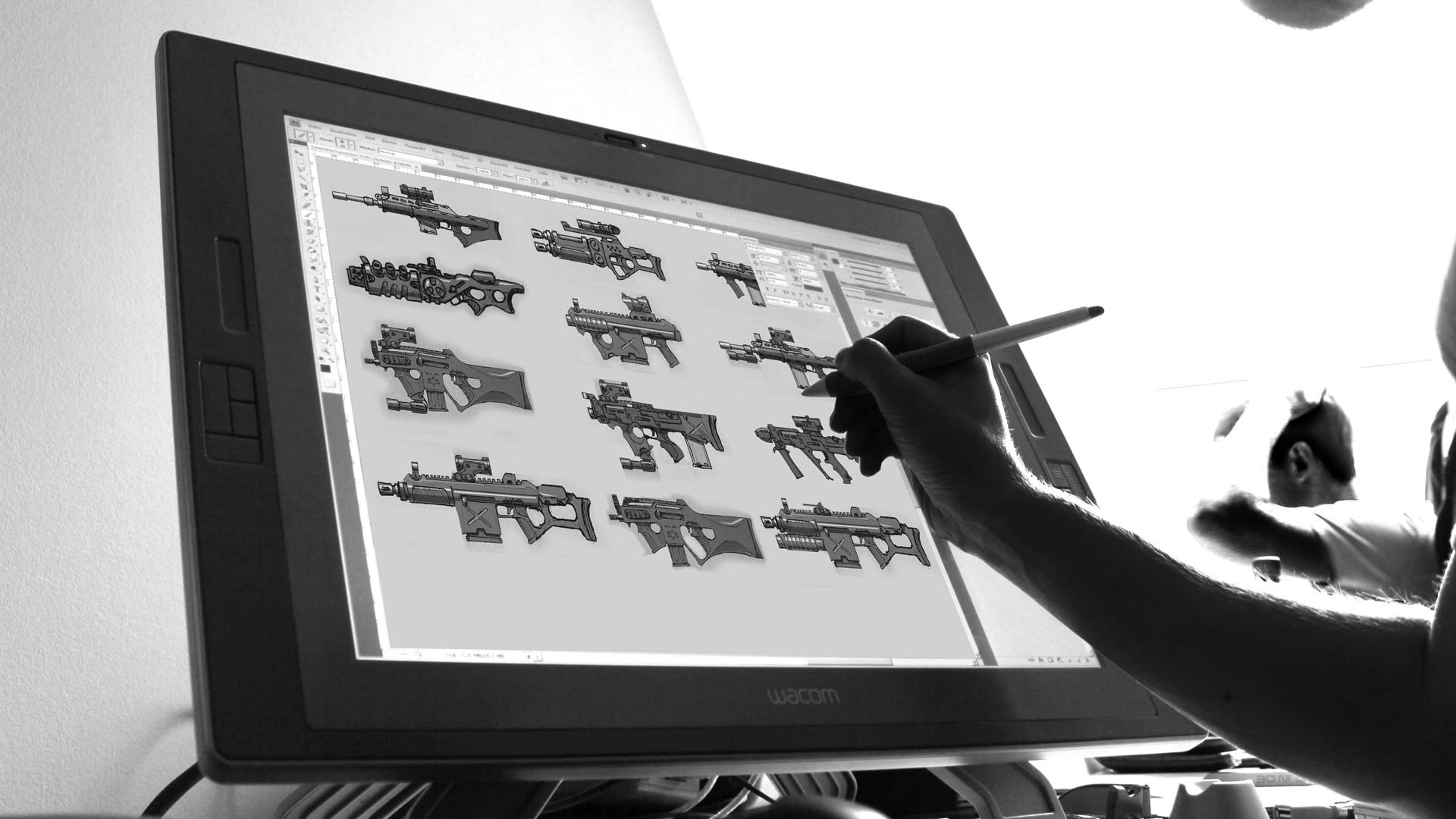 Person using a stylus on a Wacom tablet displaying digital illustrations of various futuristic guns.